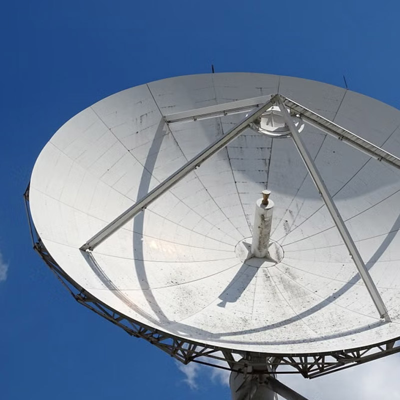 Large white satellite dish angled toward the blue sky with a central feed horn and supporting frame.